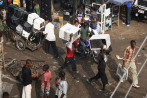 Vendors carry used air conditioners through the Alaba International Market in Lagos, Nigeria.
