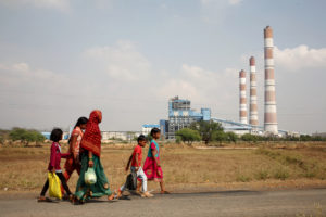 A woman and children walk past a coal-fired power plant in Chhattisgarh, India.