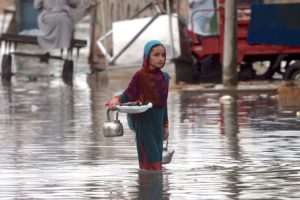 A Pakistani girl carries household belongings through a flooded street in Karachi in August 2020.