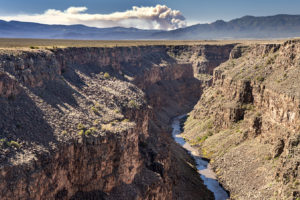 The Rio Grande River flowing through Taos Canyon in New Mexico last month, with the Calf Canyon/Hermits Peak Fire burning in the distance.
