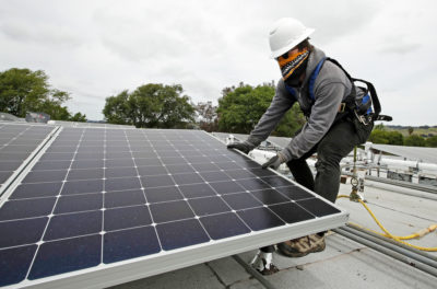 A worker installs solar panels on a house in Hayward, California amid the coronavirus outbreak.