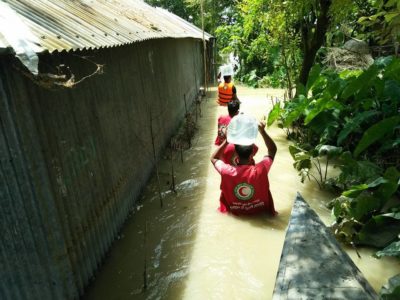 Aid workers carry drinking water to flooded communities in Bangladesh.
