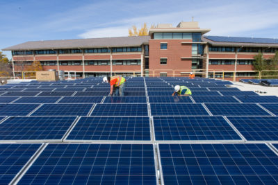 Contractors install solar panels atop Colorado State University’s Braiden Hall.