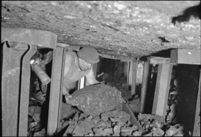 A miner lifts a lump of coal onto a conveyor belt in a mine in central England in 1944. The last of Britain's deep coal mines was closed in 2015.