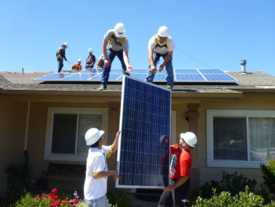 Workers install solar panels on the house of a low-income family in Los Alamos, California.