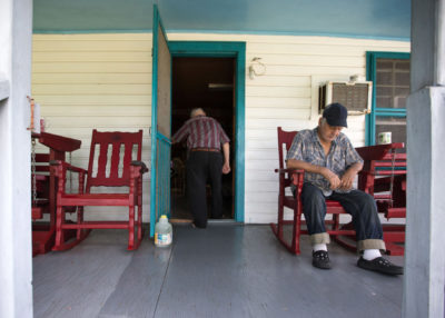 Isle de Jean Charles resident Wenceslaus Billiot (in doorway) and his wife host friends each afternoon at 3 p.m. for tea, where they sit and talk about the day. “In another 20 years there will be probably a couple feet of water around here,” he said.