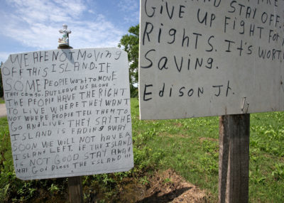 A sign on the island road, erected by Edison Dardar Jr., reflects the opposition of some residents to the proposed move to higher ground.