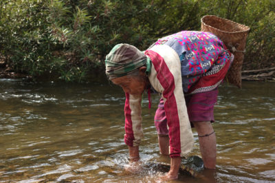 A Karen woman captures fish with a traditional net in the park.
