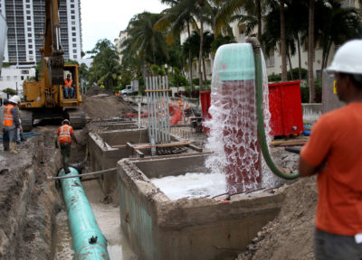 Workers install a water pump system to combat rising sea levels in Miami Beach. 
