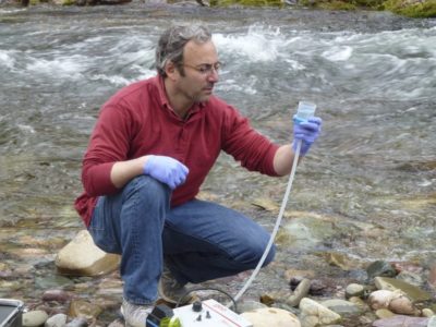 U.S. Forest Service biologist Michael Schwartz gathers water to be sampled for eDNA from Rattlesnake Creek in Montana.