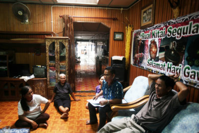 Environmentalist Jok Jau Evong (far right) and headman Gasah Anak Tadong (right, in chair) meet with community members in the Sungai Buri longhouse.