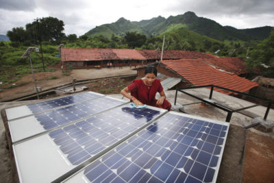 A woman inspects solar panels in the rural village of Tinginaput, India.