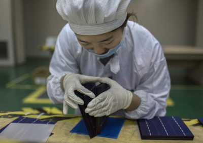 A technician inspects a solar cell on the production line at Yingli Solar in Hebei Province, China.