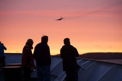 Passengers aboard the Akademik Ioffe watch as a plane arrives from the Canadian National Defence Joint Rescue Coordination Centre in Ontario. It took nine hours for the plane to get to the grounded vessel.