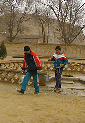 Children in rural Gansu province collect water from a well on the grounds of their school.