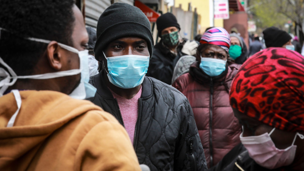 People wait in line to receive masks and food in New York City on April 18. AP PHOTO/BEBETO MATTHEWS