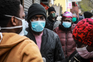 People wait in line to receive masks and food in New York City on April 18.