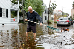 A Charleston, South Carolina resident removes debris from a drain during tidal flooding in October 2015. The city now experiences 50 days of "sunny day" flooding a year.