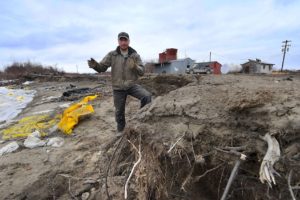 A storm-protection worker stands on the shore of the Yupik Eskimo village of Napakiak, Alaska, where melting permafrost is leading to erosion and flooding. Local leaders are considering relocating the village.
