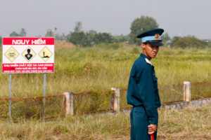A Vietnamese soldier next to a hazardous warning sign for dioxin contamination at Bien Hoa air base last October.