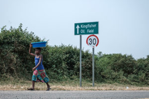 A girl walks past a sign for the Kingfisher oil field near Lake Albert in Uganda in January.