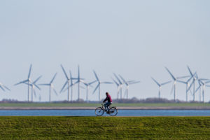 A bicyclist on an embankment in front of wind turbines in Norderney, Germany. 