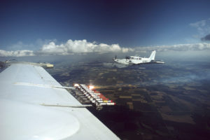 Cloud seeding equipment on the wing of plane flying over North Dakota.