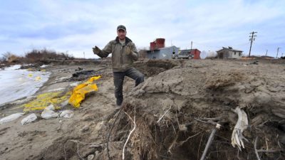 A storm-protection worker stands on the shore of the Yupik Eskimo village of Napakiak, Alaska, where melting permafrost is leading to erosion and flooding. Local leaders are considering relocating the village.