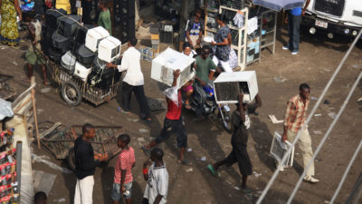 Vendors carry used air conditioners through the Alaba International Market in Lagos, Nigeria.