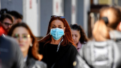 A woman wears a mask on a street in Naples, Italy this month. The country has been hit hard by the coronavirus.