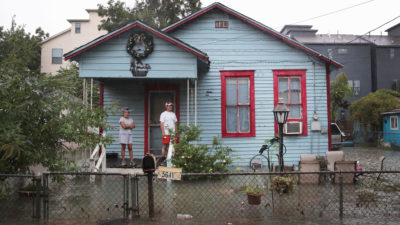 Residents of the Cottage Grove neighborhood in Houston, Texas watch as floodwaters surround their house in August 2017.