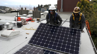 Workers install solar panels on a home in San Francisco, which has placed restrictions on the use of natural gas in new construction.