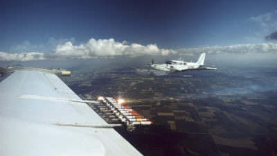 Cloud seeding equipment on the wing of plane flying over North Dakota.
