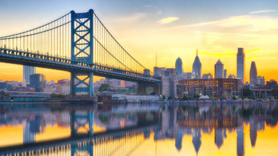The Philadelphia skyline and Benjamin Franklin Bridge reflected in the Delaware River.