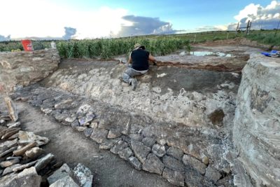 Danielle Kaye builds a berm spillway on the farm of Roberto Nutlouis. The berm holds back water, flooding the cornfield behind it.