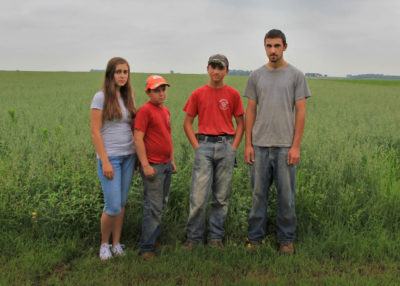 Earl Canfield of the Canfield Family Farm in Dunkerton, Iowa hauls a bag of animal feed. His children, Hannah (16), Elija (11), Andrew (14), and Mathew (18), all contribute to the farm's day-to-day operations.