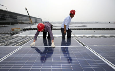 Workers install solar panels on the Hongqiao Passenger Rail Terminal in Shanghai, China.