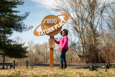 Brenda Whitfield stands in front of a sign for her block in the "Planet Streets" section of Eastwick.