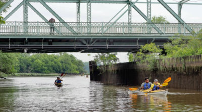 An onlooker watches from a bridge as the expedition paddles on the Cooper River.