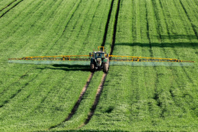 A tractor sprays fertilizer on a wheat field in North Yorkshire, England.