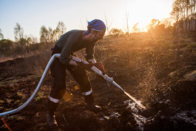 A volunteer in Russia's Smolensk region waters down fire-prone peatland in 2018.