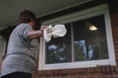 A Clairton resident wipes soot from the windows of her home.