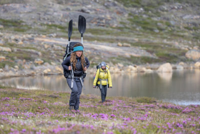University of Maine researchers Václava Hazuková and Ansley Grider hike over tundra on their way to study lakes in West Greenland.