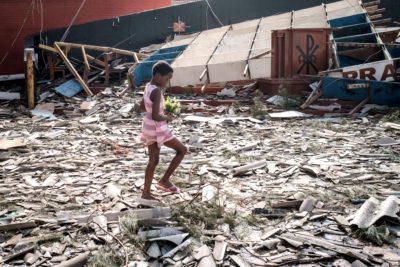 A girl collects artificial flowers from rubble left by Cyclone Idai in Beira, Mozambique in March 2019.