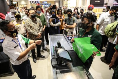 An officer directs customers to use reusable bags at a mall in Jakarta, as a ban on plastic bags takes effect, July 1, 2020.

