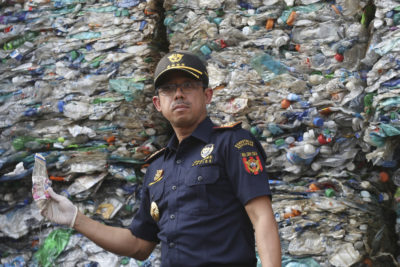 An Indonesian customs official intercepts a container full of illegally imported plastic waste in 2019.