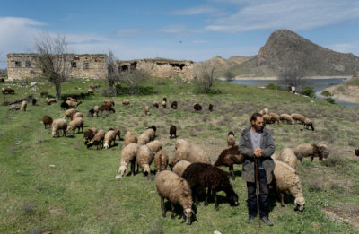 Cihan Çal watches over his sheep near the Keban Dam reservoir on the Euphrates in Turkey. The farmhouse behind him was abandoned after the dam flooded pastureland.