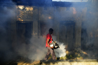 A worker sprays insecticide in a crowded neighborhood in Dhaka to protect against dengue fever, July 18, 2023.