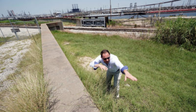 Engineer Steve Sherrill of the U.S. Army Corps of Engineers shows how much height is being added to seawalls and levees near a refinery in Port Arthur, Texas, in July 2018. 