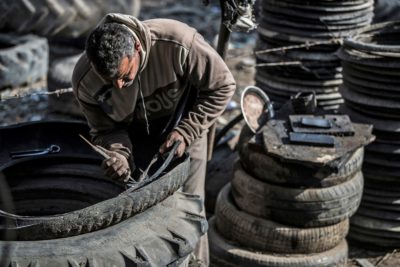 A worker takes apart a tire at a recycling shop in Mit al-Harun, Egypt.